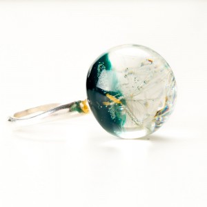 Pierścionek z zielonym oczkiem i dmuchawcem.