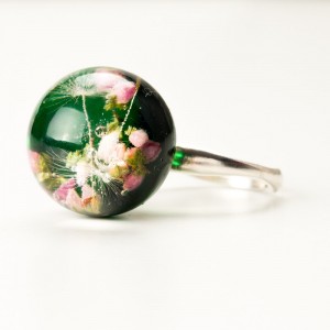 Pierścionek z motywem kwiatowym i zielonym tłem.