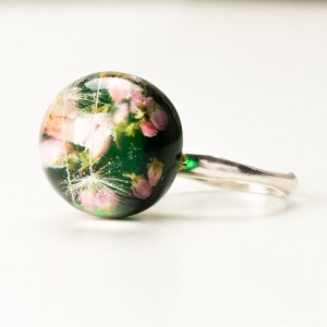 Pierścionek z motywem kwiatowym i zielonym tłem.