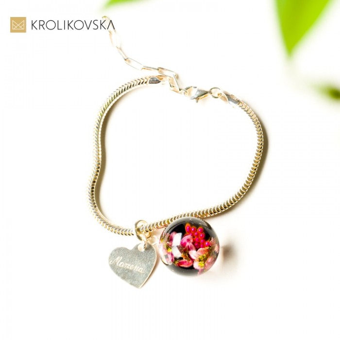 Bransoletka z różowymi kwiatami w zawieszce.