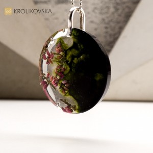 Naszyjnik ciemno zielony z kwiatami zatopionymi w żywicy.