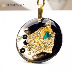 Artystyczny naszyjnik z żywicy, na której złote detale tworzą rysunek.